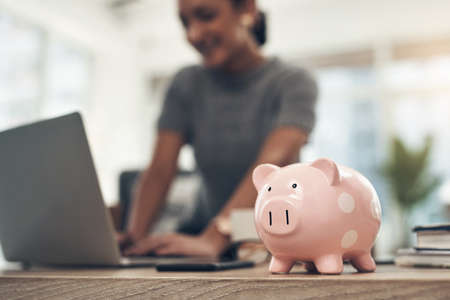 Finance, banking and saving money with piggybank, investing and planning while working on a laptop...