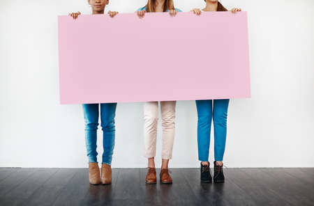 Something for the ladies... Cropped studio shot of a group of young women holding a blank placard against a white background.の写真素材