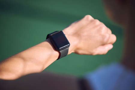 Athlete checking watch time, heart rate and step count during run, exercise or jog outdoors. Fit,...