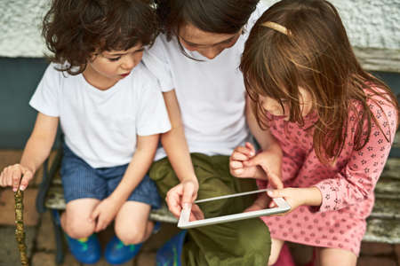 Engaged in a whole wide world online. three adorable little children using a digital tablet while...