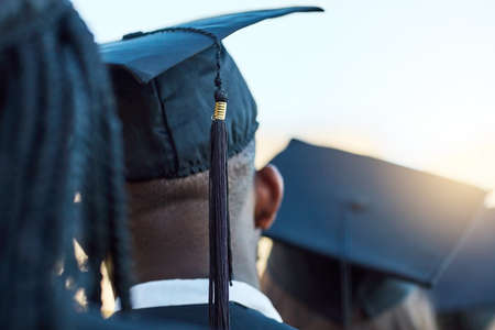 Time to step into a new world. Rearview shot of a group of students standing in a line on graduation...