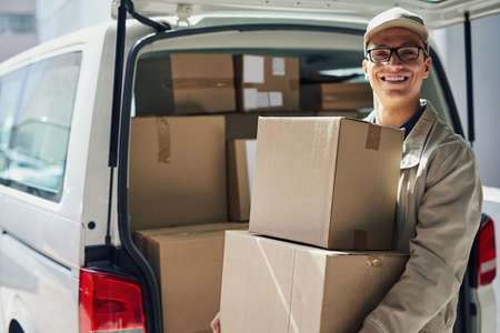 Ill be making a delivery stop by you soon. Portrait of a courier moving boxes in a delivery van.の写真素材