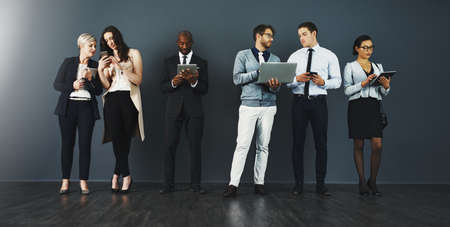 Staying productive with wireless connections. Studio shot of a group of businesspeople using various...