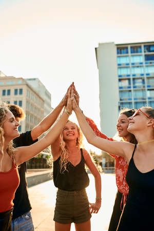 Own the city. a group of young friends high fiving while out in the city.