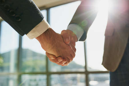 You have a deal. Full length shot of two unrecognizable businessmen shaking hands in the office.の写真素材