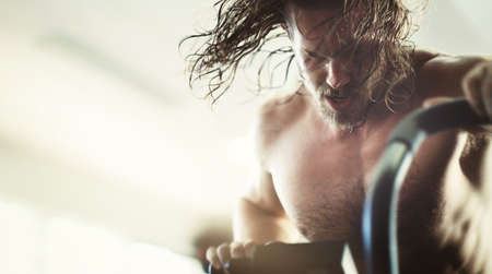 He goes all out. Low angle shot of a handsome young man looking full of determination while working...