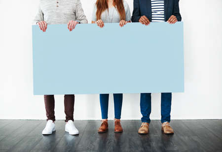 The blue says it all. Cropped studio shot of a group of people holding a blank placard against a white background.の写真素材
