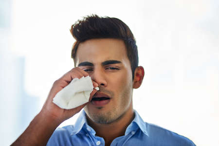 I need to get home and rest. a young businessman blowing his nose at work.