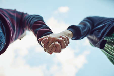 Hold tight and never let go. Low angle shot of an affectionate couple holding hands outdoors.の写真素材