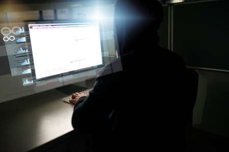 Hes caught up in the code. Rearview shot of an unrecognizable male computer programmer working on...