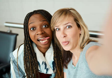 This trip is gonna be fun. Cropped portrait of two young girlfriends taking selfies in the departure...