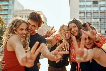 Peace out. Cropped portrait of a group of young friends flashing peace signs while out in the city.の写真素材