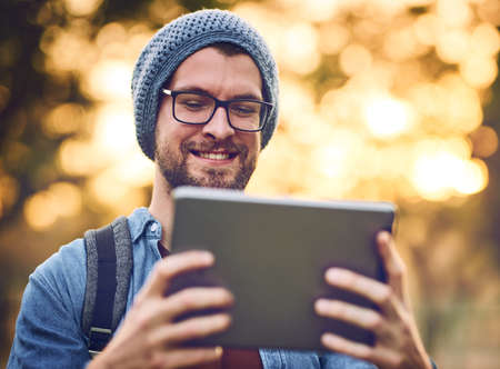 Technology and the outdoors can go together. a handsome young man using a tablet outdoors.