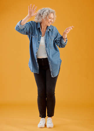 Fun, happy and cheerful woman dancing, celebrating and enjoying life alone against an orange...