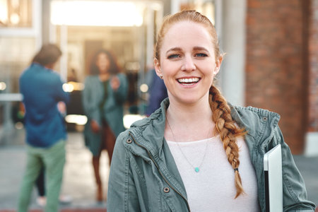 All about that college life. Portrait of a happy young woman standing outdoors on campus.の写真素材