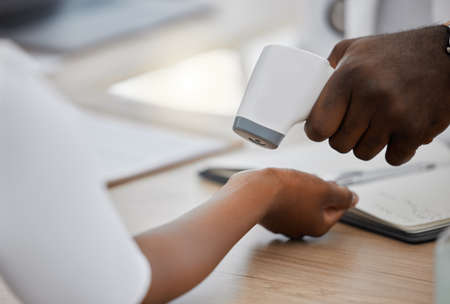Doctor checking wrist temperature of sick covid patient to test for fever, risk of disease or flu. Closeup on hands scanning with laser thermometer for healthcare and virus safety in medical hospitalの写真素材