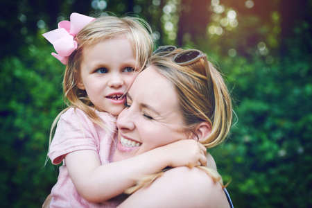 Squeezes for my sweet little girl. an adorable little girl bonding with her mother during a day outdoors.の写真素材