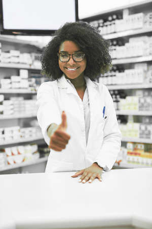 We always got your heath covered. Portrait of a cheerful young female pharmacist showing thumbs up while looking at the camera in a pharmacy.の写真素材
