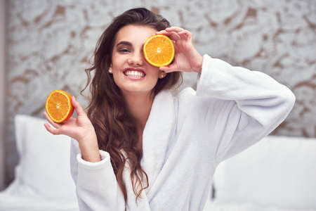 I see some vitamin C. an attractive young woman holding up orange halves.の写真素材