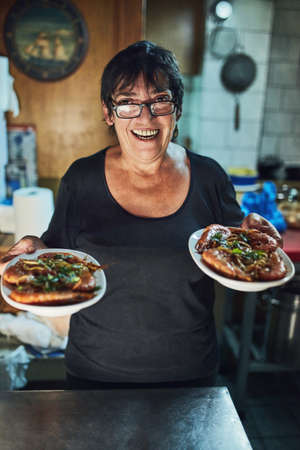 She serves the best dishes. a mature woman working in a restaurant.の写真素材