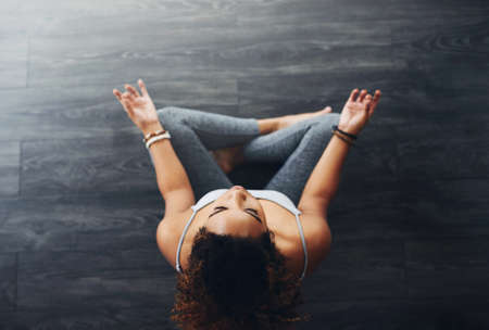 Great health starts with meditation. High angle shot of a young woman practising yoga.の写真素材