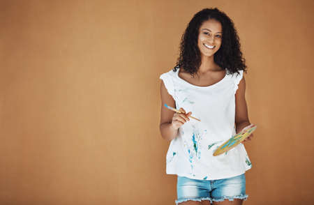 Art your heart out. Portrait of an attractive young female painter in the studio.の写真素材