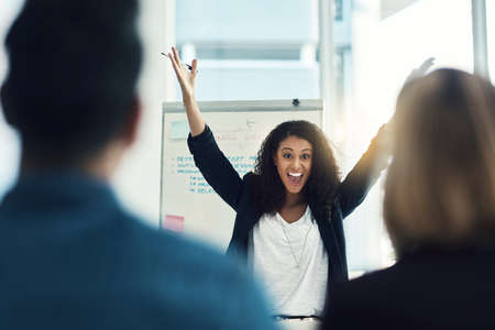 We did it. a young businesswoman cheering excitedly during a brainstorming session with colleagues in a modern office.の写真素材