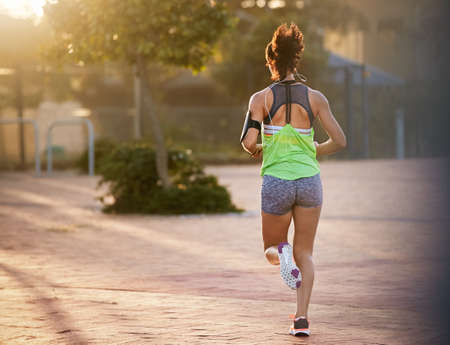 Going the distance. Rear view shot of a sporty young woman out for a run.の写真素材