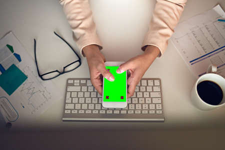 She never does business without this app. High angle shot of an unrecognizable businesswoman using a...