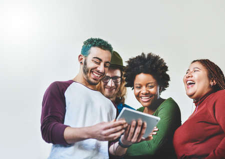 How the connected generation connect. Studio shot of a group of young people using a digital tablet...