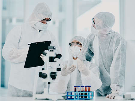 Science and medical research doctors working on covid vaccine test while wearing protective hazmat...