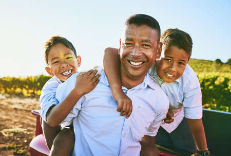 Father and son time. a cheerful father spending quality time with his two young sons while smiling and looking at the camera outside.の写真素材