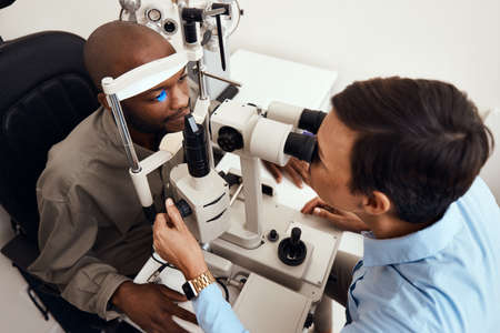 Eye, vision or sight test or exam of a patient above at an optometrist, optician or ophthalmologist. Testing and checking eyesight on a ophthalmoscope for optical glasses or contact lenses at clinic.の写真素材