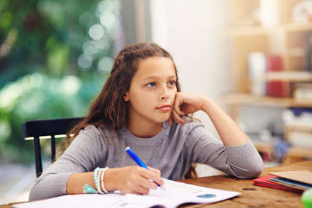 A young girl doing homework inside.
