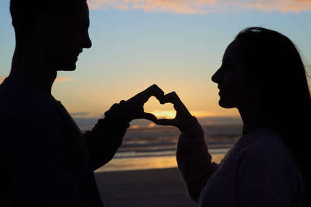 Love lights up the soul. Silhouette shot of a young couple on the beach.の写真素材