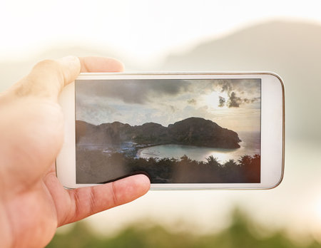 This view is worth remembering. an unidentifiable person taking a picture with a smartphone while on holiday.の写真素材