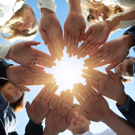 Coming together as one. Low angle shot of a group of businesspeople joining their hands together in unity.の写真素材