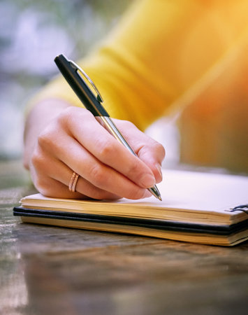 Sometimes your story just has to come out. a woman sitting at a table and writing in her notepad.の写真素材