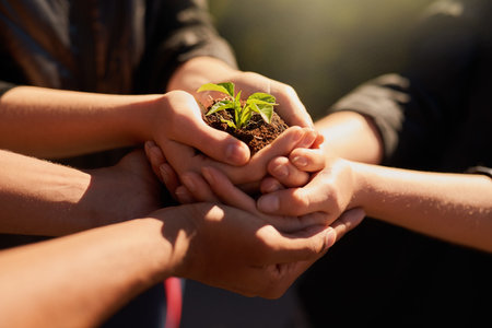 Be the change you want to see. a group of people holding a plant growing out of soil.の写真素材