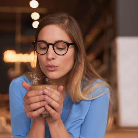 Its a bit hot...an attractive young woman sitting in a coffee shop.の写真素材