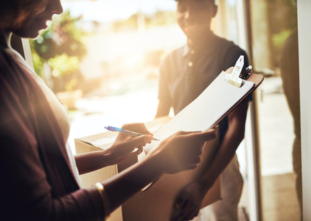 It couldnt be simpler. High angle shot of an unrecognizable woman signing for a home delivery.の写真素材