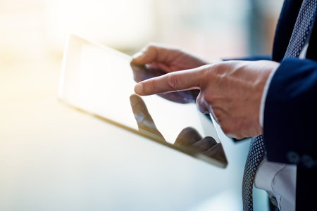 Modern tools for the modern man. Cloesup shot of a businessman using a digital tablet while standing...