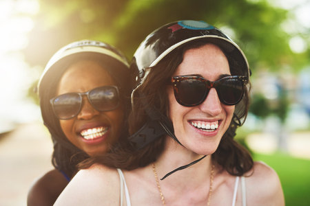 The fun just never stops. two friends enjoying a ride on a scooter together.の写真素材