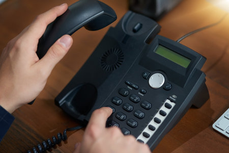 Making that important call. an unrecognizable man dialling a number on a telephone.の写真素材