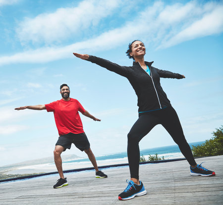 Exercising outside increases the fun factor. a couple doing yoga outdoors.の写真素材