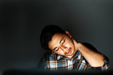 Long hours are taking their toll. a young designer massaging his sore neck while working on his...