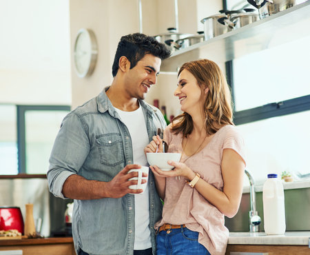 Their home is full of smiles. an affectionate young couple standing in their kitchen.の写真素材