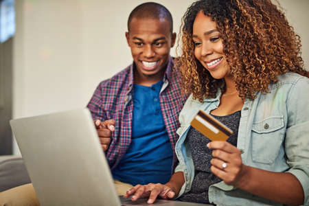 So many things to buy for the house. a cheerful young couple doing online shopping together while...