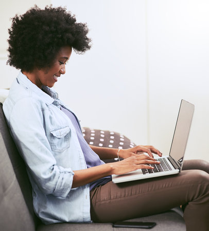 Working on something her blog followers will love. a young woman using a laptop on the sofa at home.の写真素材