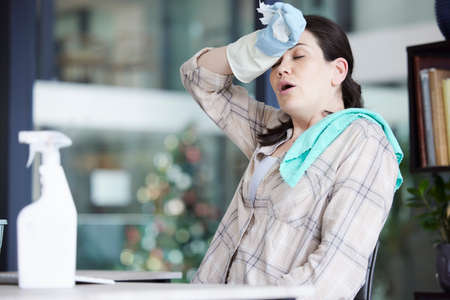Tired, stressed and frustrated cleaning lady resting after doing chores, hygiene and housework alone...